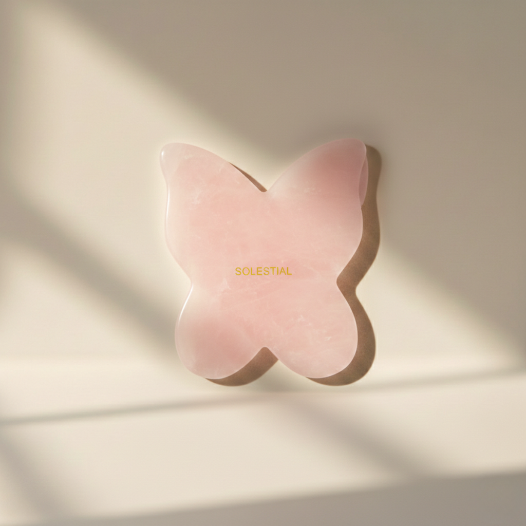 Solestial Rose Quartz Pink butterfly-shaped Gua Sha tool with 'Solestial' branding on a beige background